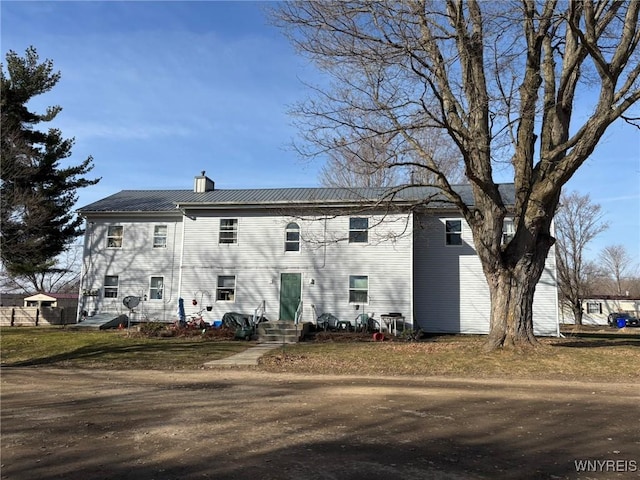 rear view of house with a chimney and metal roof