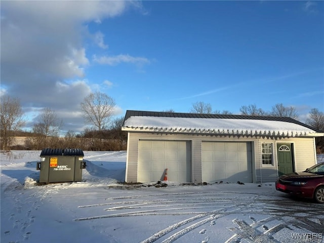 snow covered garage featuring a detached garage