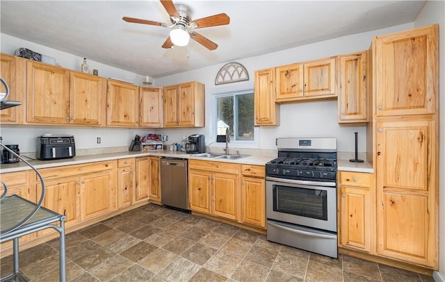 kitchen with a ceiling fan, a sink, light countertops, appliances with stainless steel finishes, and stone finish flooring