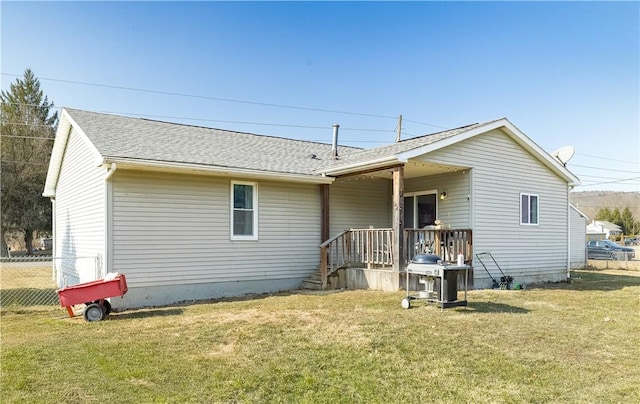 rear view of property with fence, a yard, and roof with shingles