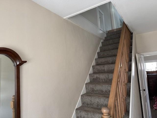 staircase featuring baseboards and carpet floors