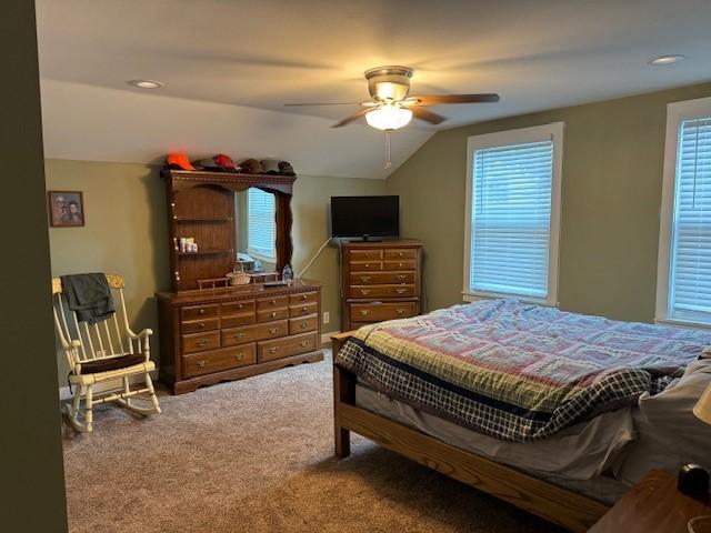 carpeted bedroom featuring multiple windows, a ceiling fan, and lofted ceiling