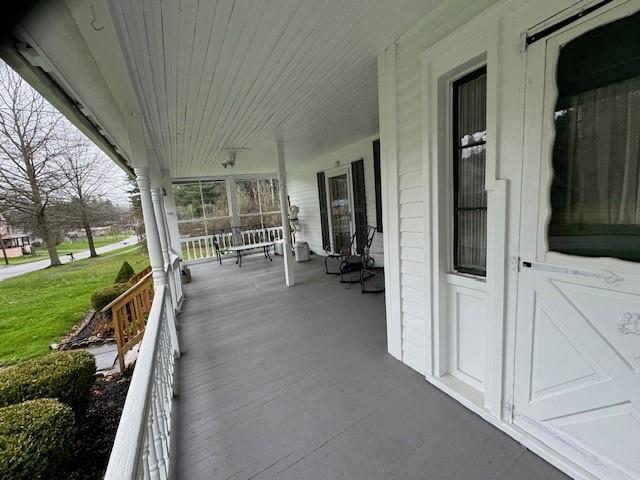 wooden deck featuring a lawn and covered porch