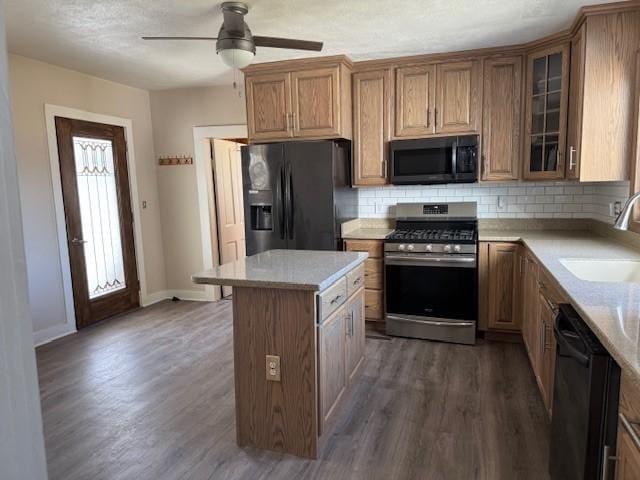 kitchen featuring a sink, backsplash, black appliances, and wood finished floors