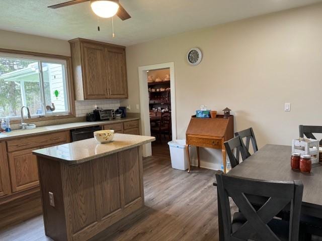 kitchen with light wood-type flooring, a sink, light countertops, decorative backsplash, and dishwasher