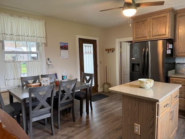 kitchen with a kitchen island, dark wood finished floors, light countertops, fridge with ice dispenser, and a ceiling fan