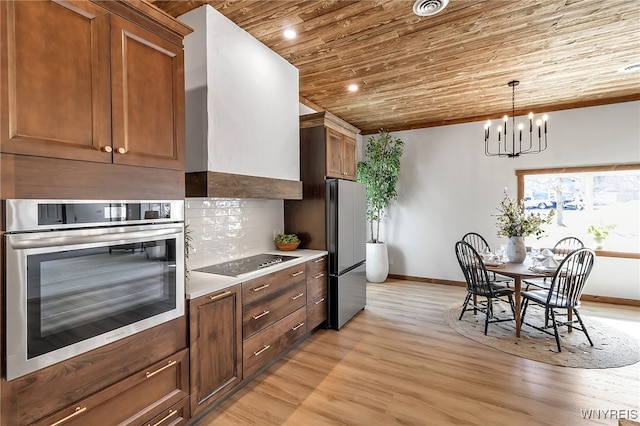 kitchen with black electric stovetop, stainless steel oven, wooden ceiling, freestanding refrigerator, and exhaust hood