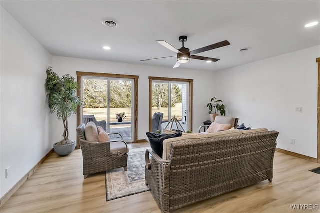 living room with visible vents, baseboards, light wood-style floors, and ceiling fan