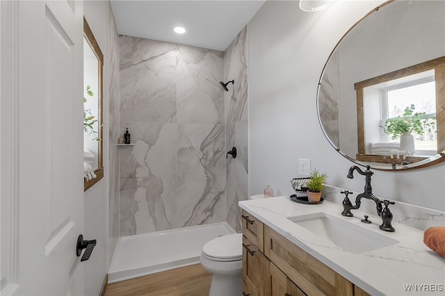 full bathroom with a marble finish shower, toilet, wood finished floors, and vanity