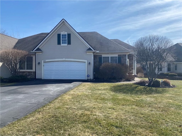 view of front of house with a front yard, roof with shingles, an attached garage, stone siding, and aphalt driveway