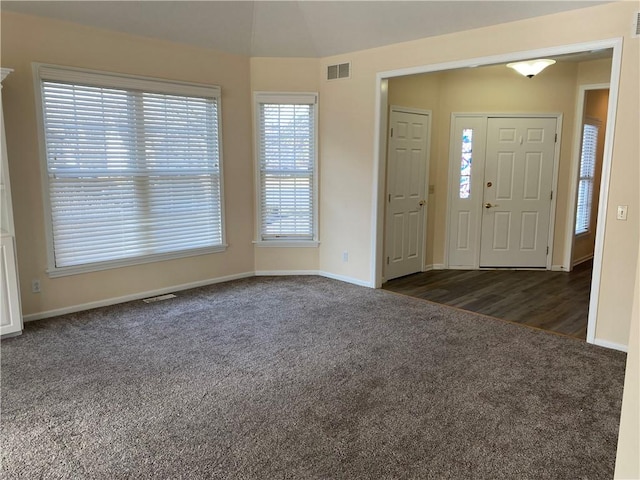 foyer featuring dark colored carpet, visible vents, and baseboards