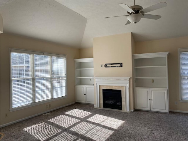 unfurnished living room featuring carpet flooring, a fireplace with flush hearth, ceiling fan, and vaulted ceiling