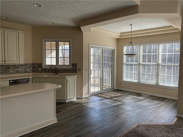 kitchen featuring tasteful backsplash, a sink, dishwasher, white cabinets, and dark wood-style flooring