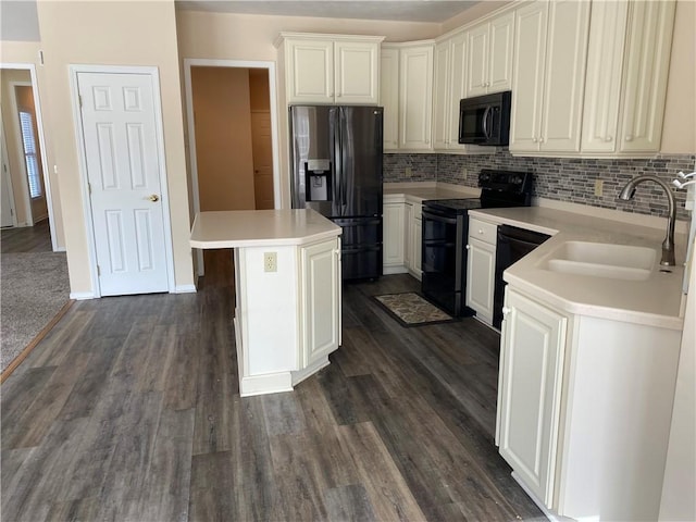 kitchen with backsplash, dark wood finished floors, light countertops, black appliances, and a sink