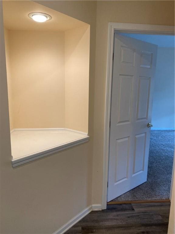 hallway featuring baseboards and dark wood-style flooring