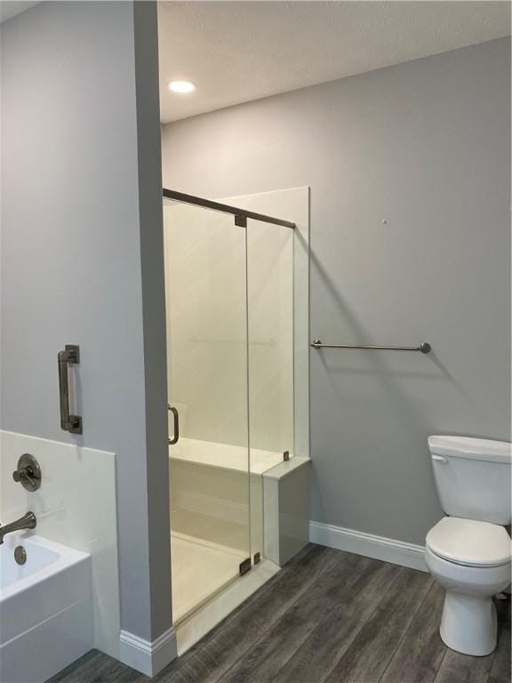 full bathroom with a bath, a shower stall, toilet, and wood finished floors