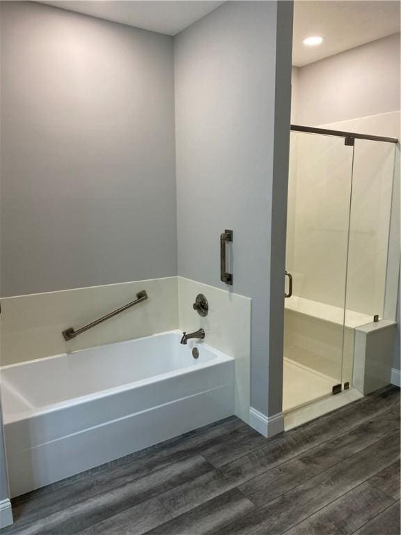 full bathroom featuring a stall shower, wood finished floors, and a bath