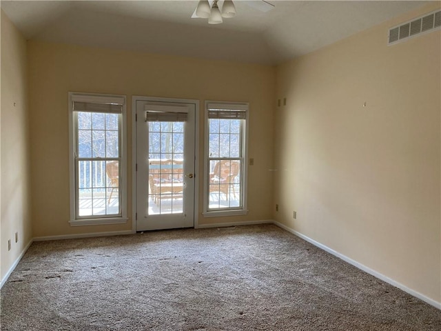 carpeted spare room featuring visible vents, baseboards, ceiling fan, and vaulted ceiling