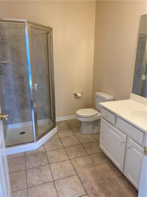 full bath with tile patterned floors, toilet, a stall shower, and vanity