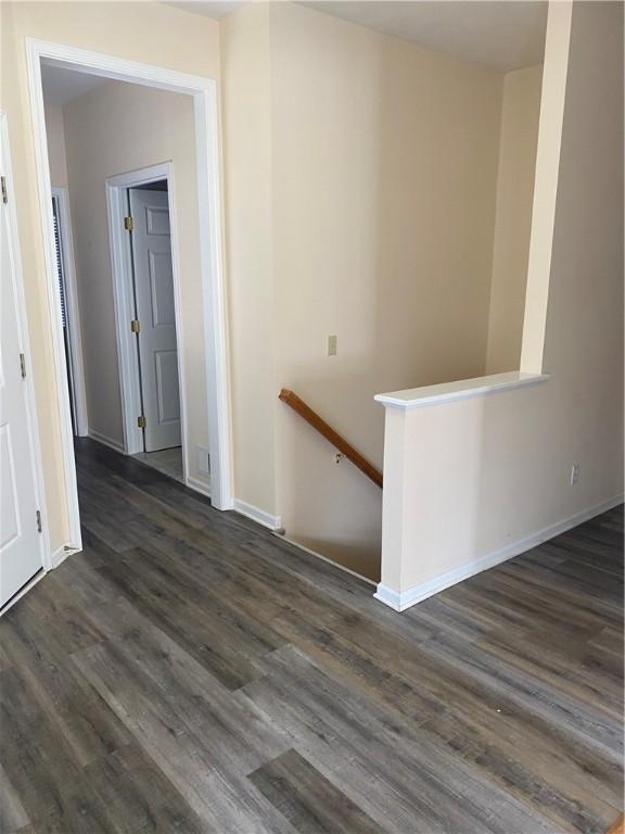 interior space with an upstairs landing, dark wood-style floors, and baseboards