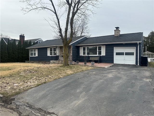 ranch-style house with driveway, a chimney, and an attached garage