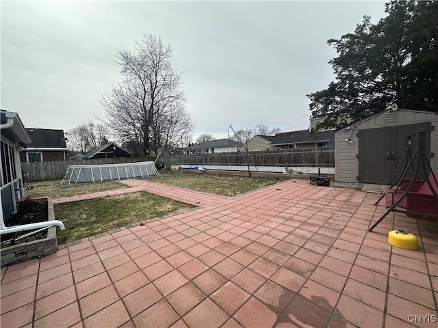 view of patio / terrace featuring an outdoor structure, a storage unit, a fenced backyard, and an outdoor pool