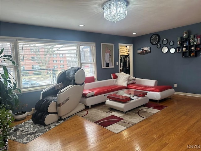 living room featuring a chandelier, baseboards, and wood finished floors