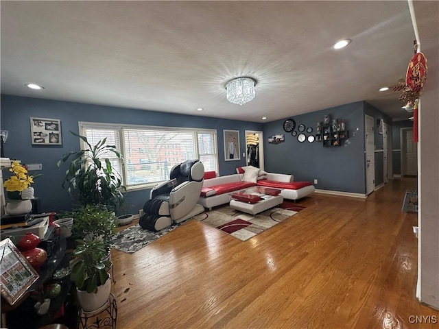 unfurnished living room with an inviting chandelier, recessed lighting, wood finished floors, and baseboards