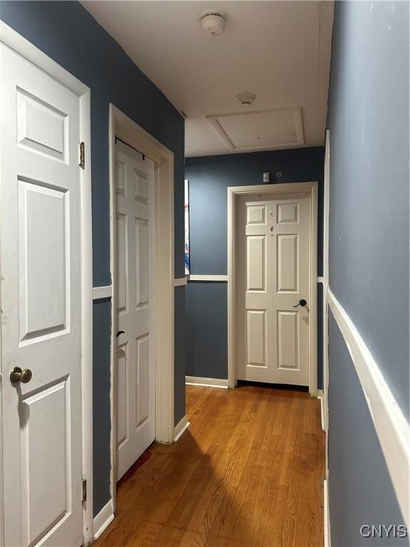 corridor with attic access, wood finished floors, and baseboards