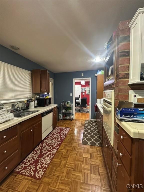 kitchen with a sink, dark brown cabinetry, dishwasher, and light countertops