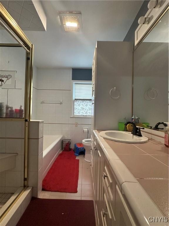 bathroom featuring vanity, a stall shower, tile patterned floors, toilet, and tile walls