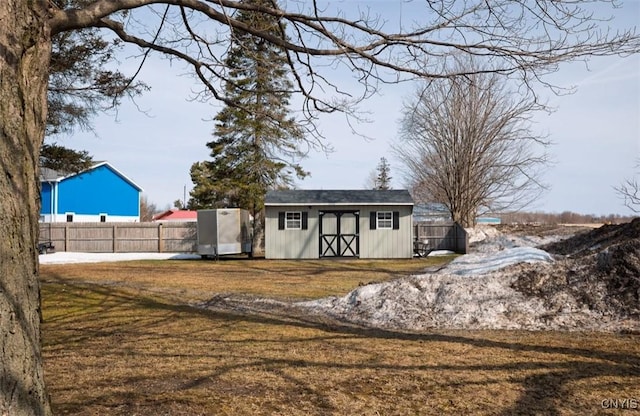 view of front of home with a storage shed, an outdoor structure, a front lawn, and fence