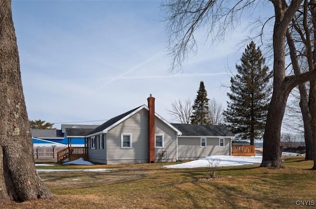 rear view of property featuring a chimney and a yard