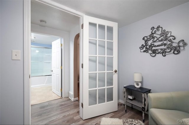 living area with arched walkways, baseboards, and wood finished floors