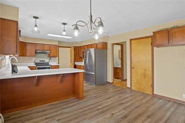 kitchen featuring a peninsula, a sink, decorative backsplash, light countertops, and stainless steel appliances