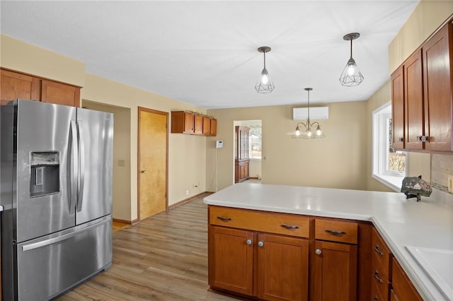 kitchen with a peninsula, light countertops, stainless steel refrigerator with ice dispenser, and brown cabinets