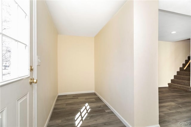 hallway featuring baseboards, wood finished floors, and stairs