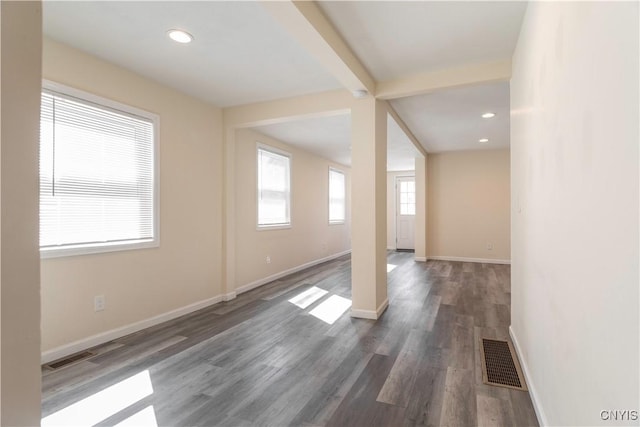 spare room with beamed ceiling, wood finished floors, visible vents, and baseboards