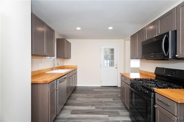 kitchen featuring gas stove, a sink, stainless steel dishwasher, light wood-type flooring, and butcher block counters