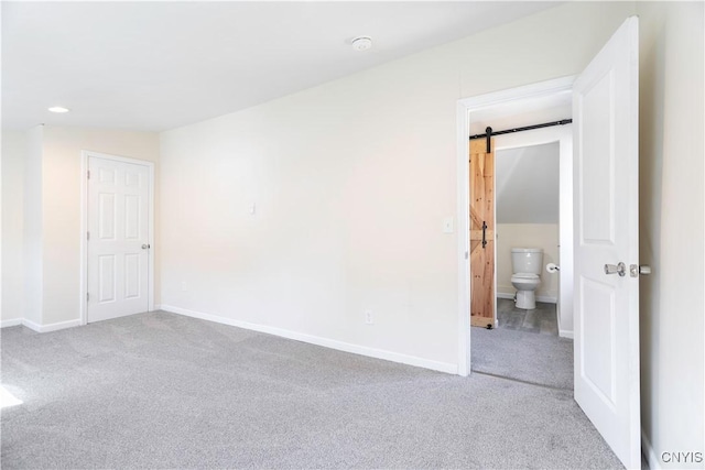 spare room with recessed lighting, a barn door, baseboards, and carpet