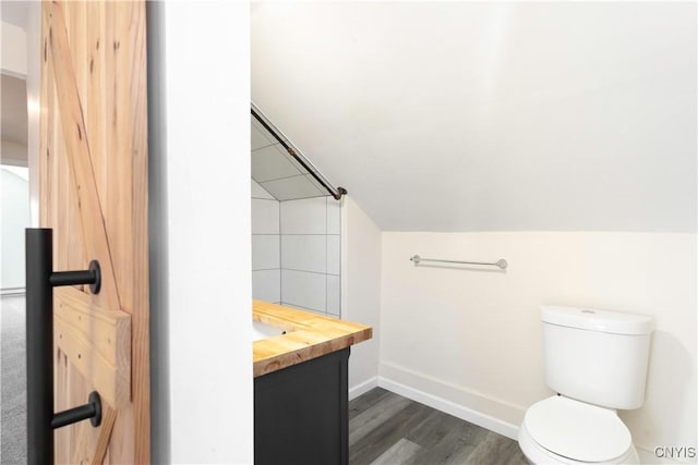 bathroom featuring baseboards, toilet, vaulted ceiling, wood finished floors, and vanity