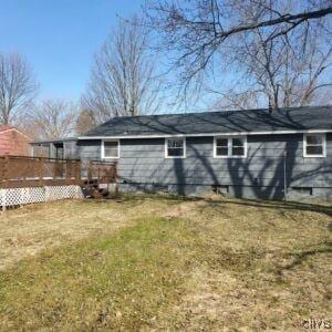 rear view of house featuring a lawn and a deck