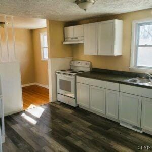 kitchen featuring white electric stove, dark wood finished floors, a sink, under cabinet range hood, and a textured ceiling