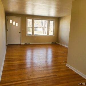 unfurnished living room featuring wood finished floors and baseboards