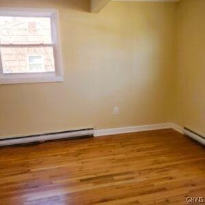 unfurnished room featuring a baseboard radiator, baseboards, and wood finished floors