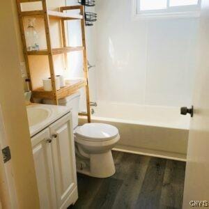 full bath featuring shower / bath combination, toilet, vanity, and wood finished floors