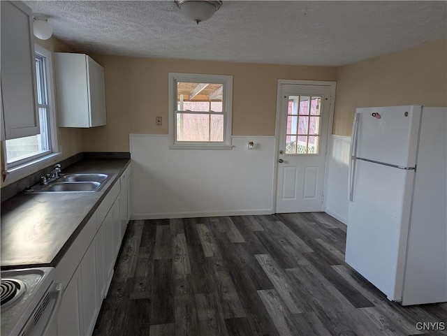 kitchen featuring a wainscoted wall, a textured ceiling, dark wood-style flooring, and freestanding refrigerator