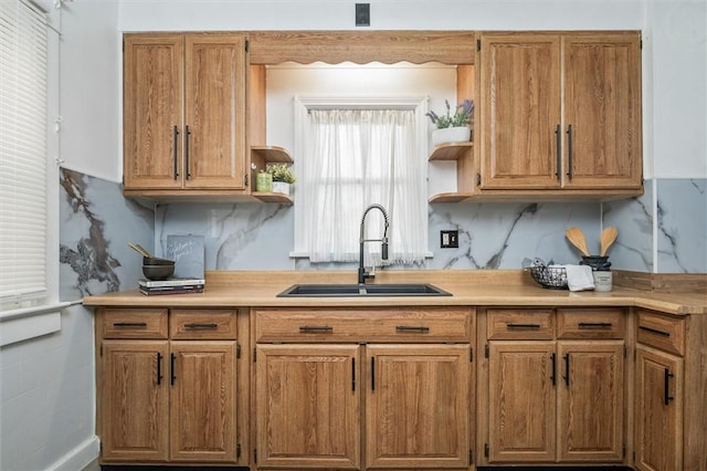 kitchen featuring open shelves, light countertops, brown cabinets, and a sink