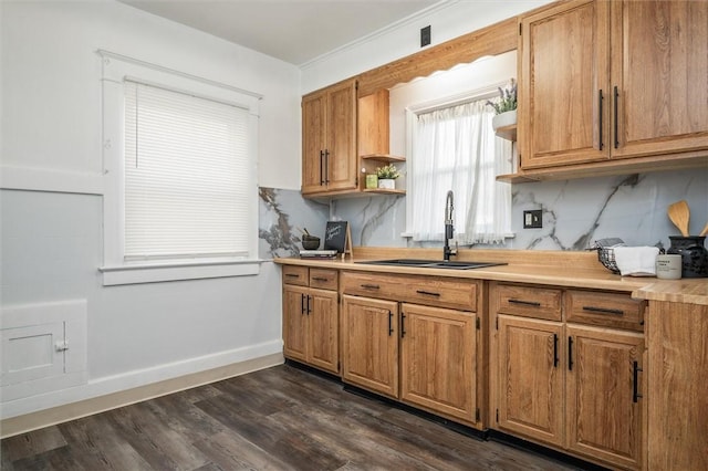 kitchen with baseboards, light countertops, decorative backsplash, dark wood-style floors, and a sink