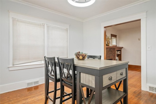 dining space with visible vents, crown molding, and wood finished floors